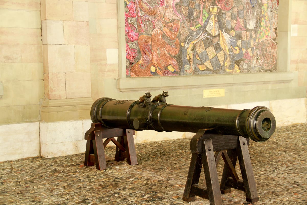 Canons sous l'arcade de l'Ancien Arsenal de Genève, en Vieille-Ville, évoquant la défense pénale et la justice.